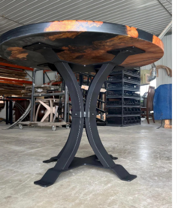 Hourglass-style steel pedestal base mounted to a dining tabletop, featuring a matte black powder-coated finish and heavy-duty welded construction for commercial use.