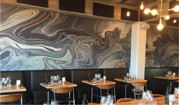 Restaurant interior with marble-patterned wall and tables.