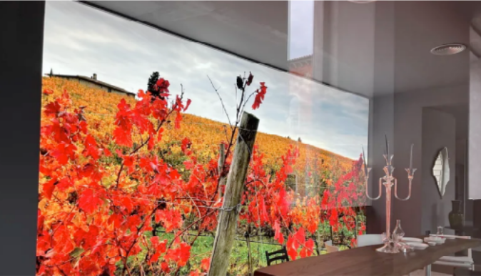 Large light box displaying a scenic landscape with red foliage in a modern living room.