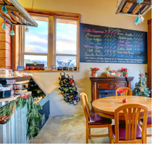 Dining area with a chalkboard menu, wooden table, and chairs in a cozy interior setting.