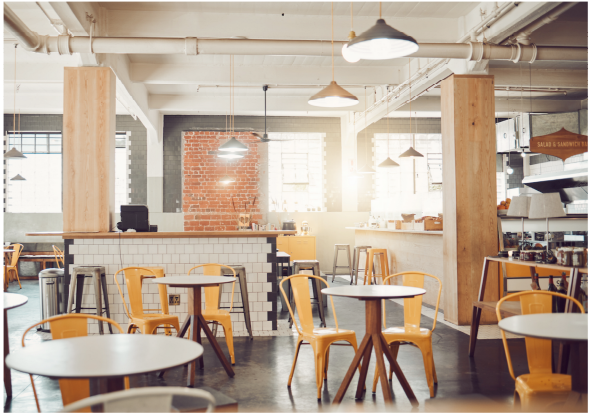 Modern cafe interior with tables, chairs, and a brick wall.