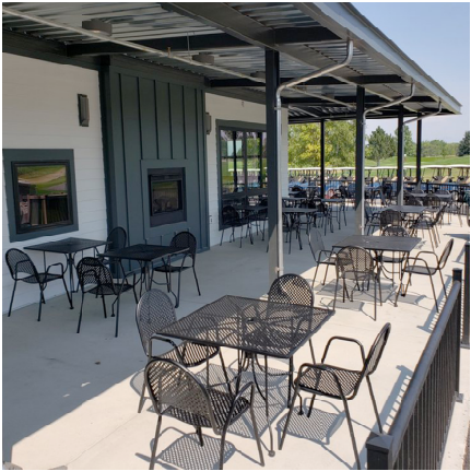Outdoor seating area with tables and chairs under a covered patio.