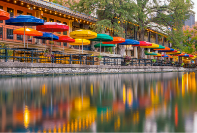 Colorful umbrellas reflected in a body of water with a building in the background