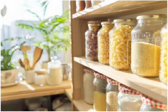 Kitchen shelves with jars of pasta and grains, plants in the background